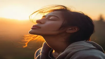 Person breathing deeply at sunrise overlook.