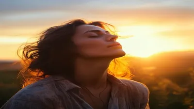Person breathing deeply at sunrise overlook.