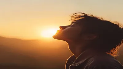 Person breathing deeply at sunrise overlook.