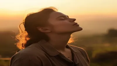 Person breathing deeply at sunrise overlook.
