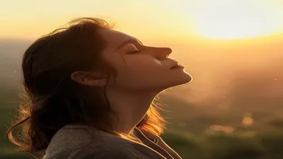 Person breathing deeply at sunrise overlook.