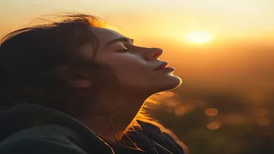 Person breathing deeply at sunrise overlook.