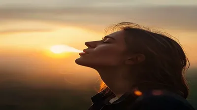 Person breathing deeply at sunrise overlook.