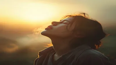 Person breathing deeply at sunrise overlook.
