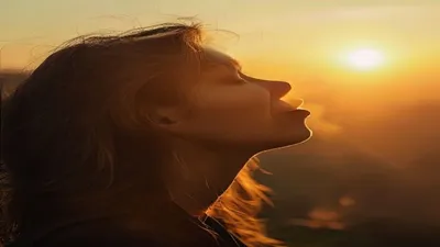 Person breathing deeply at sunrise overlook.