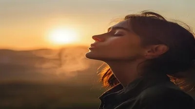 Person breathing deeply at sunrise overlook.