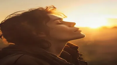 Person breathing deeply at sunrise overlook.