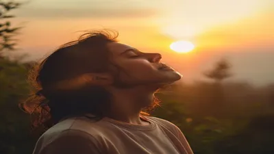 Person breathing deeply at sunrise overlook.