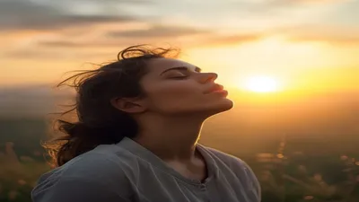 Person breathing deeply at sunrise overlook.
