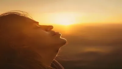 Person breathing deeply at sunrise overlook.
