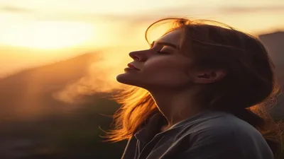 Person breathing deeply at sunrise overlook.