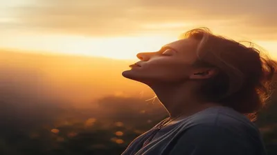 Person breathing deeply at sunrise overlook.