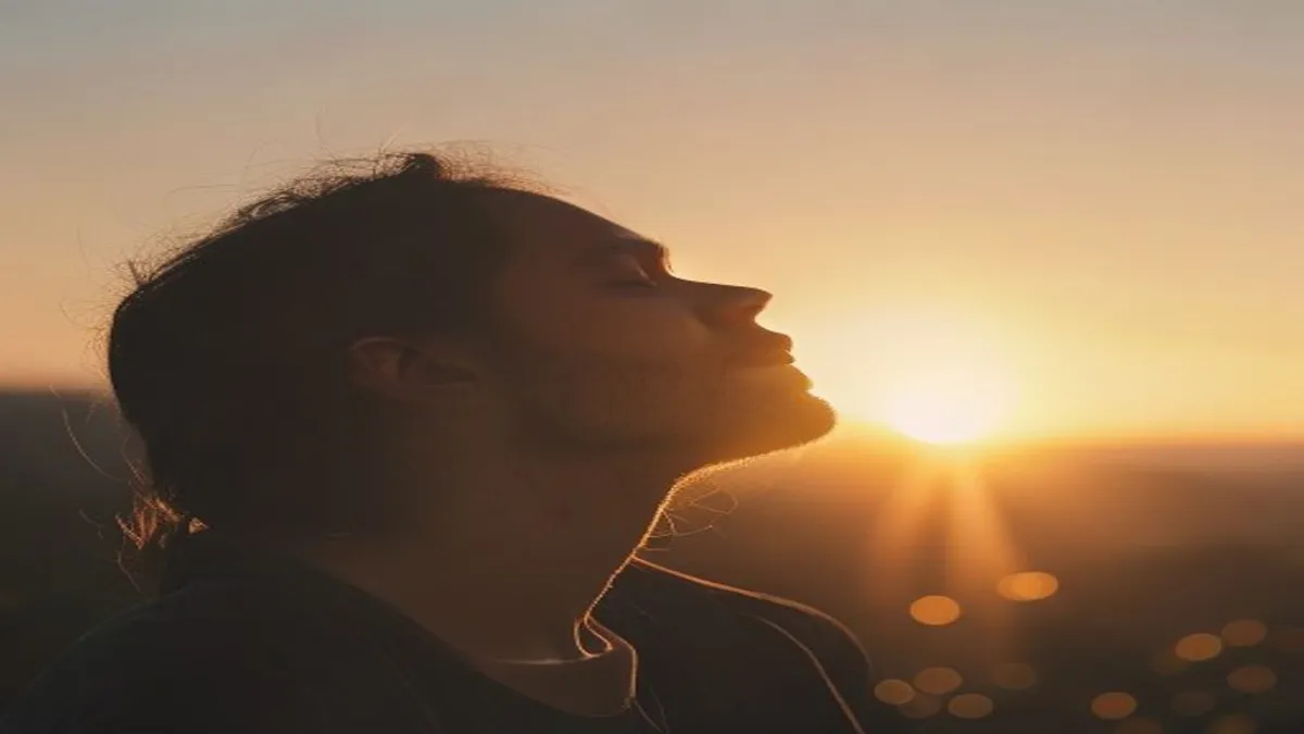 Person breathing deeply at sunrise overlook.