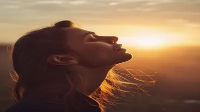 Person breathing deeply at sunrise overlook.
