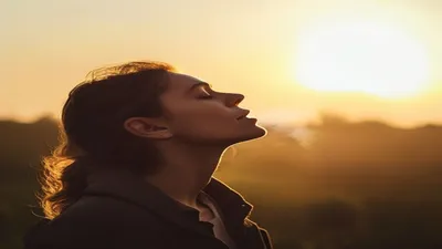 Person breathing deeply at sunrise overlook.