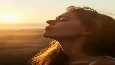 Person breathing deeply at sunrise overlook.