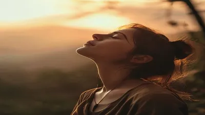 Person breathing deeply at sunrise overlook.