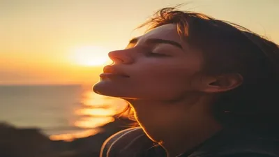 Person breathing deeply at sunrise overlook.